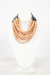 Black leather with beige layered bead necklace displayed on plain bust and on a marble surface
