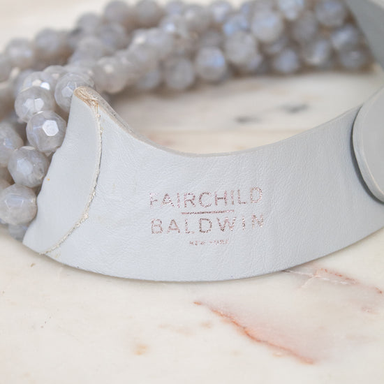 Close-up of 'Fairchild Baldwin Ney York' faded branding stamp on gray leather section displayed on top of a marble slab