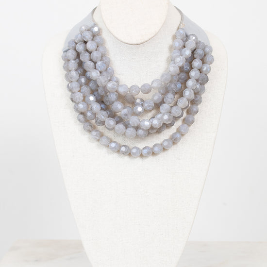 Gray layered beaded necklace with gray leather and magnetic closure displayed on a plain bust against a plain background