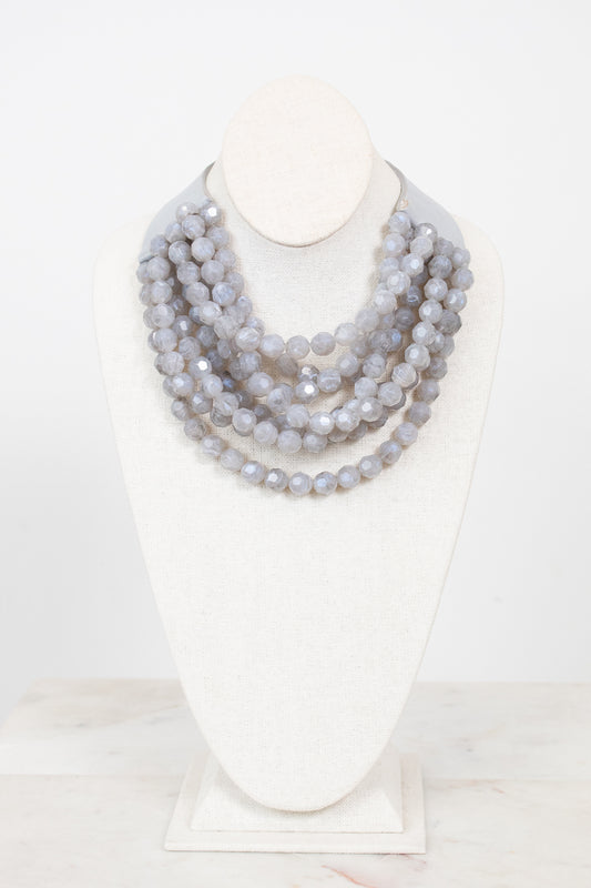 Gray layered beaded necklace with gray leather and magnetic closure displayed on a plain bust against a plain background