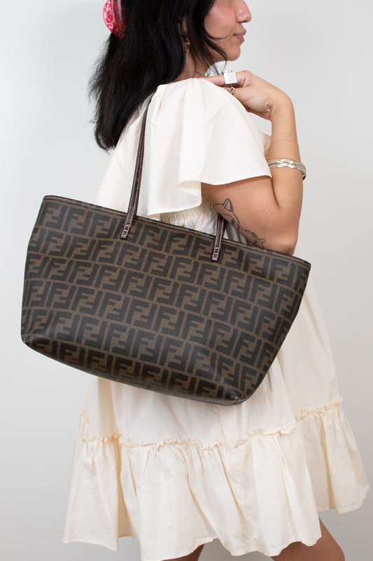 Model carrying Fendi handbag with a prominent FF logo on a white background