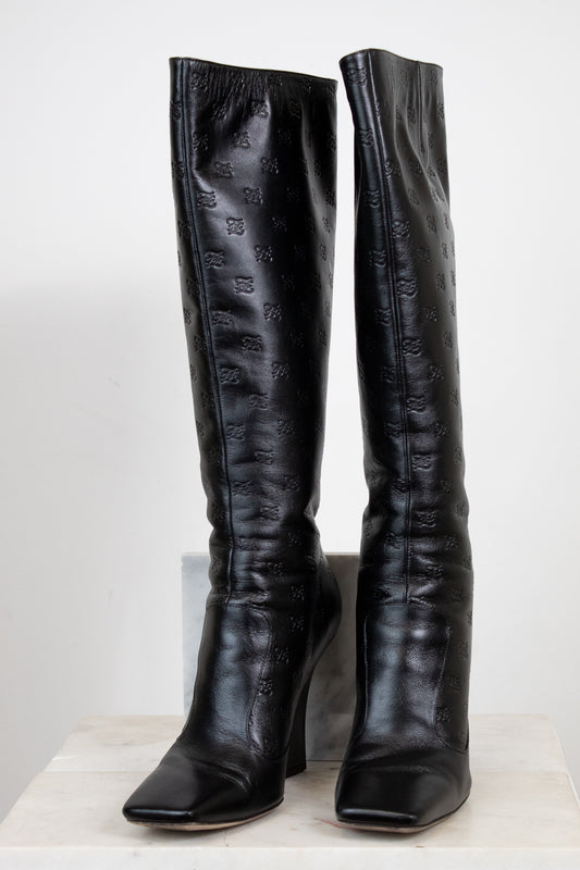 Black knee-high boots with a pattern on a white background