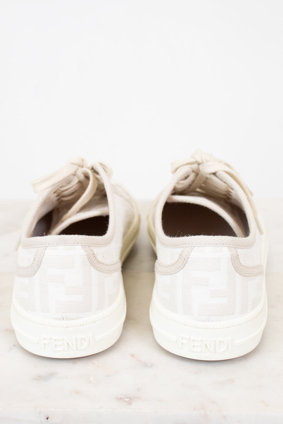 Pair of white sneakers on a light marble surface