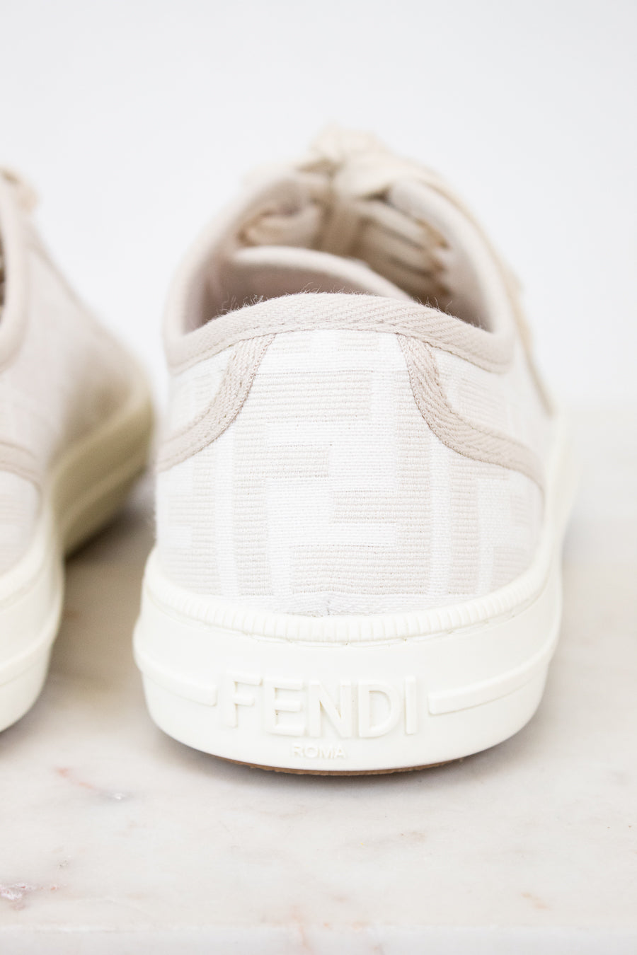 White Fendi sneakers on a light marble background