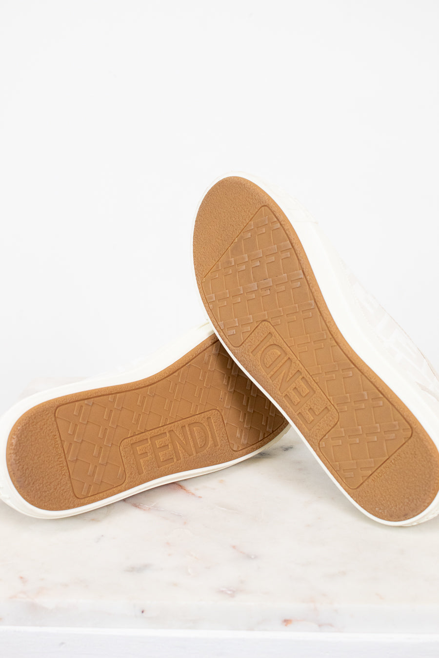 Tan shoe insoles with 'Fendi' branding on a white background