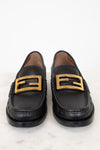 Black loafers with gold buckles on a white background