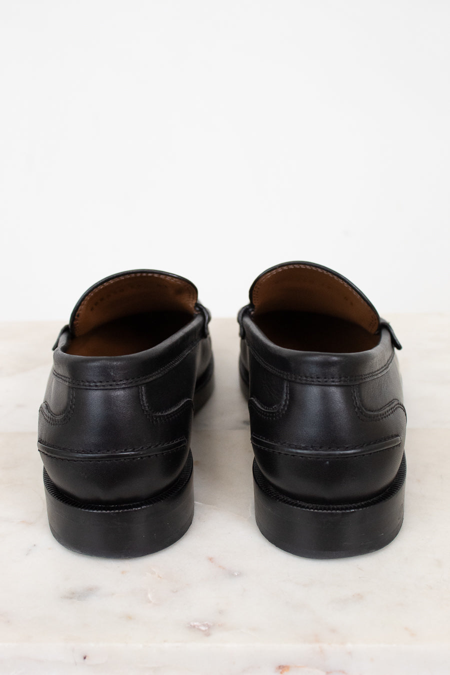 Pair of black leather shoes on a light marble surface