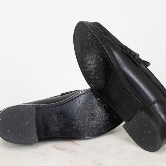 Black shoes with black soles on a white marble surface