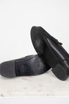 Black shoes with black soles on a white marble surface