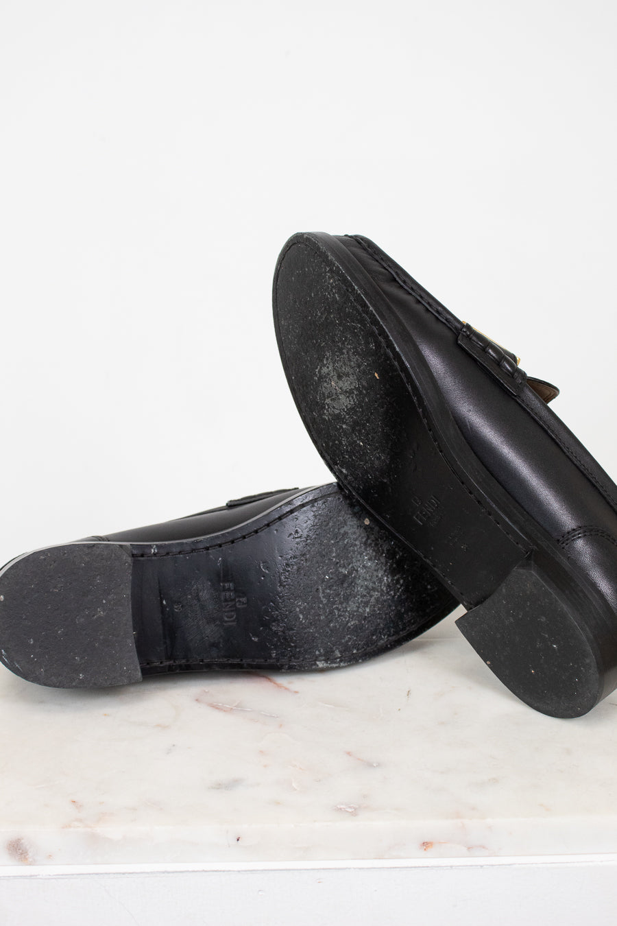 Black shoes with black soles on a white marble surface
