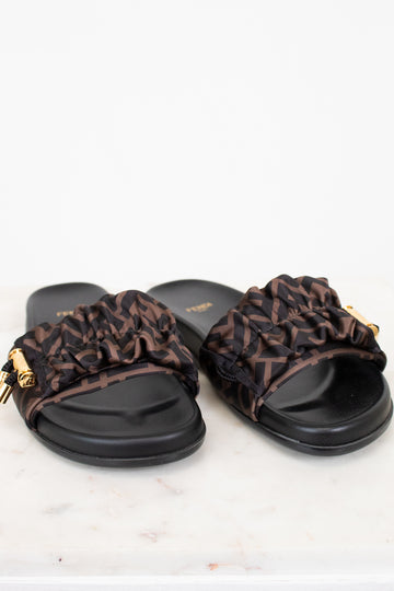 Pair of black slides with Zucca print straps on a white background