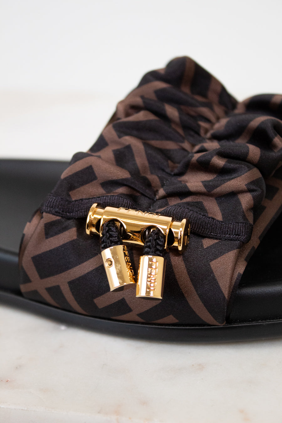 Brown patterned sandal with gold clasp on a white background