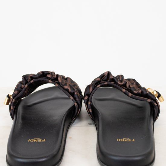 Pair of black sandals with gold accents on a white background
