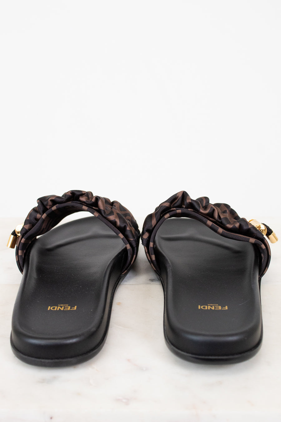 Pair of black sandals with gold accents on a white background