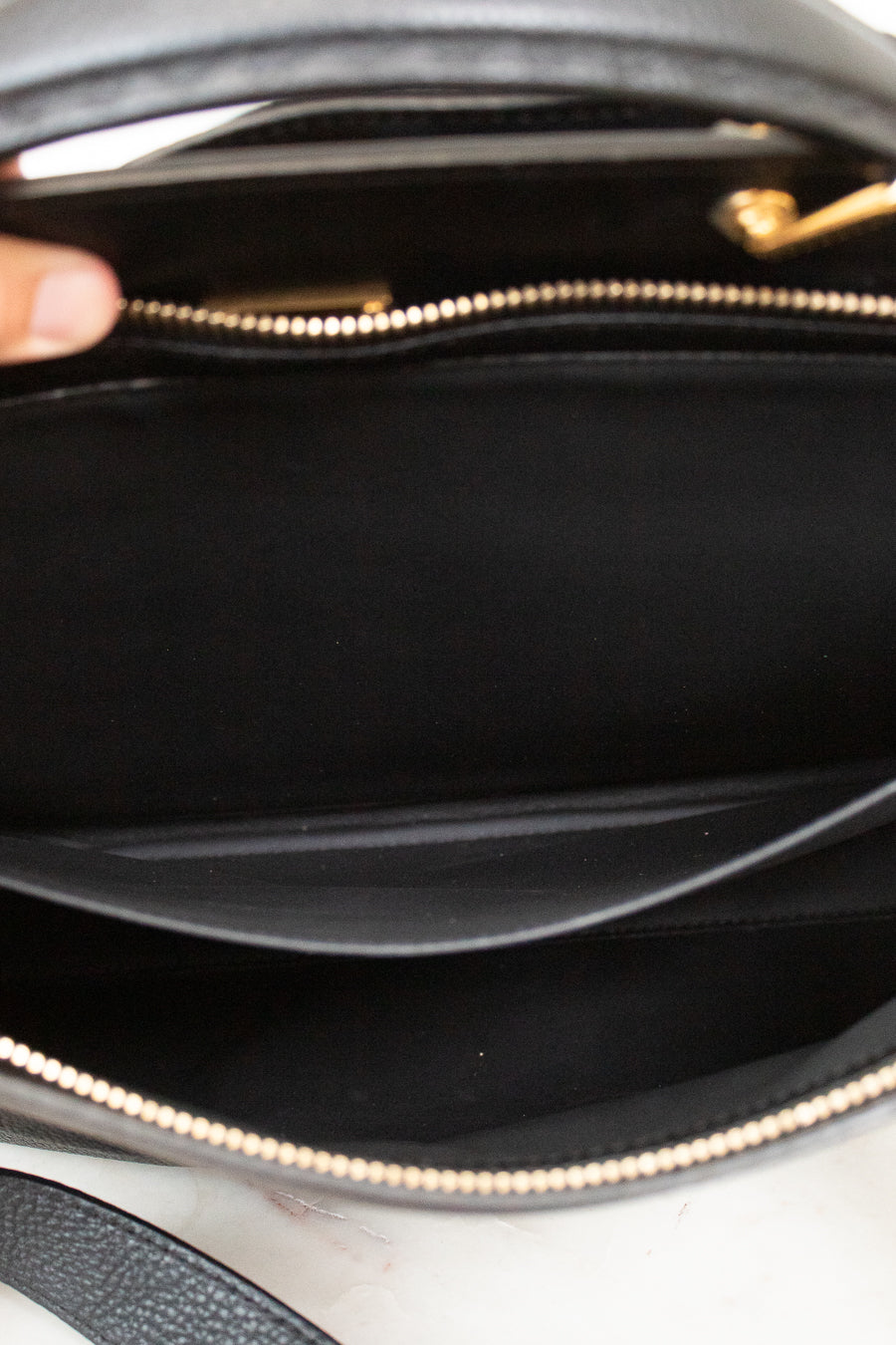 Close-up of a black handbag with a gold zipper