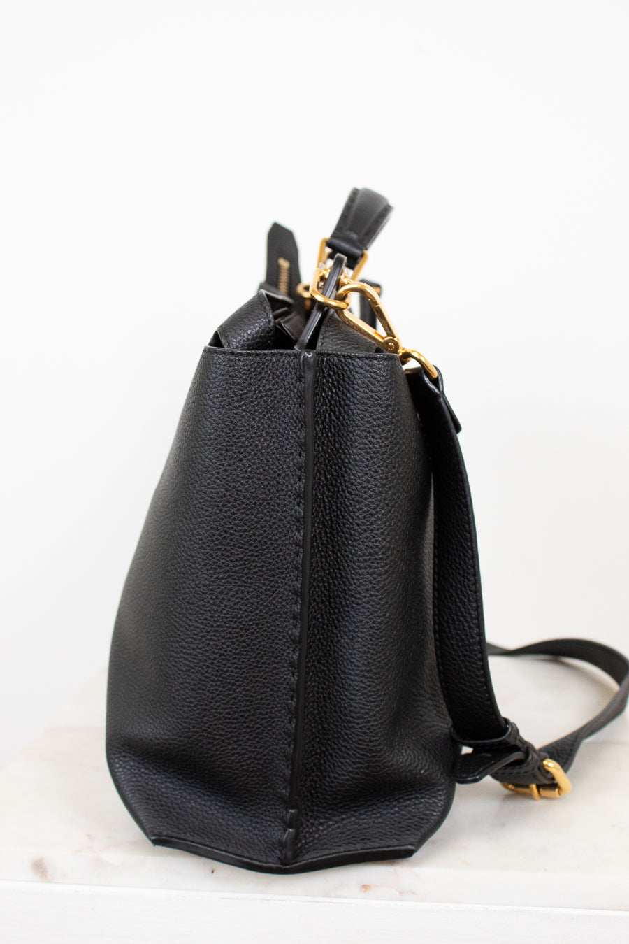 Black leather handbag with gold zipper on a white background