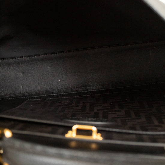Close-up of a black handbag with a gold clasp on a white background
