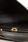 Close-up of a black handbag with a gold clasp on a white background
