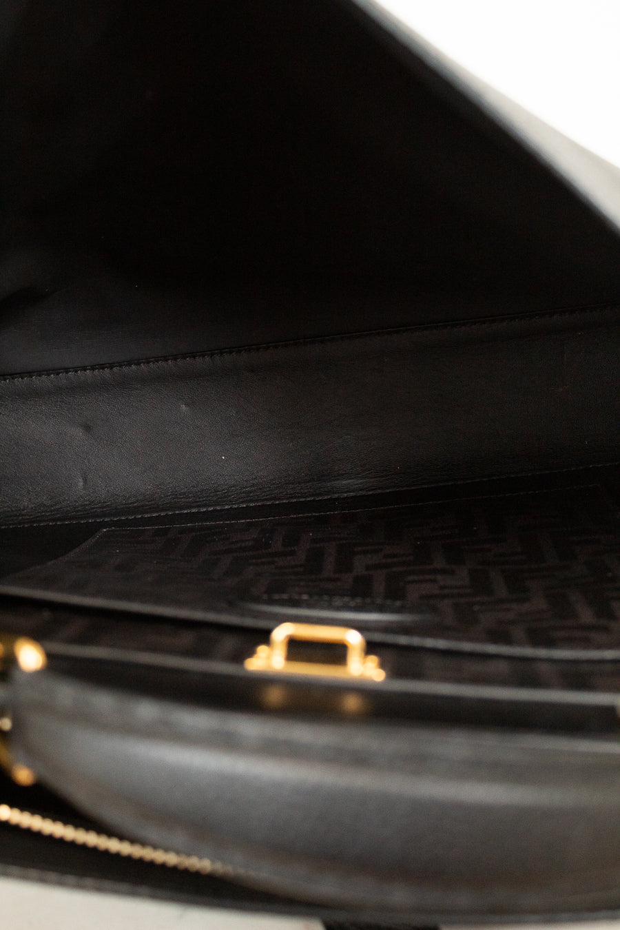 Close-up of a black handbag with a gold clasp on a white background