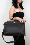Black handbag held by a person against a white background