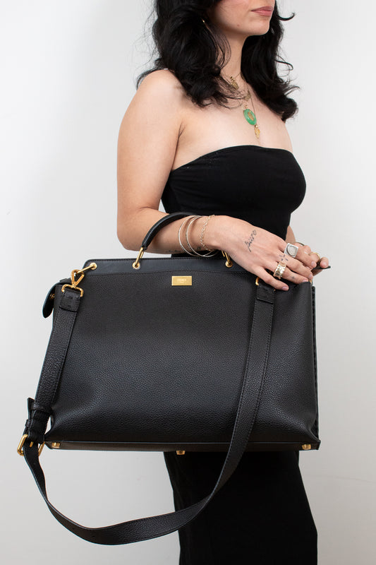Black handbag held by a person against a white background