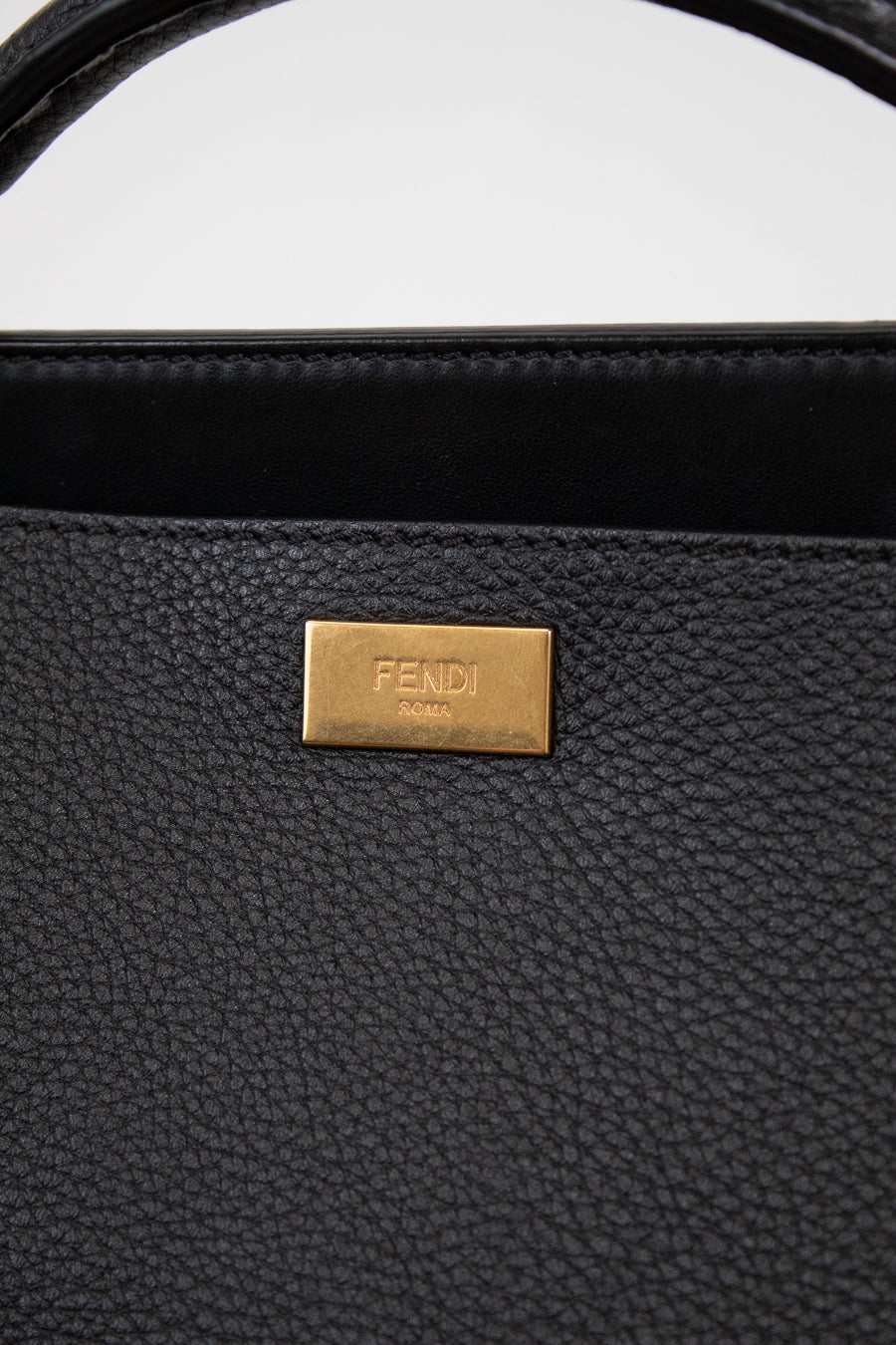 Black handbag with a gold Fendi logo on a white background
