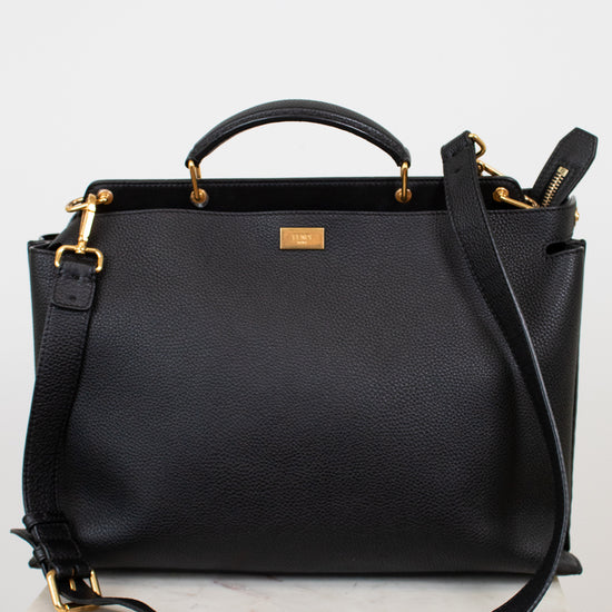 Black leather handbag with gold accents on a white background