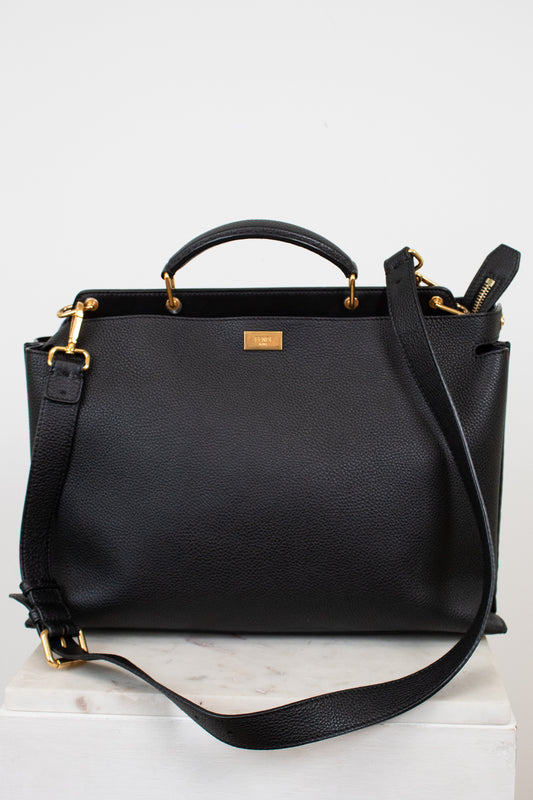 Black leather handbag with gold accents on a white background