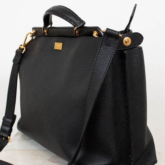 Black leather handbag with gold accents on a white background
