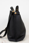 Black leather handbag with gold zipper on a light gray background