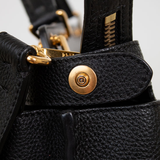 Close-up of a black leather bag with gold hardware on a light gray background