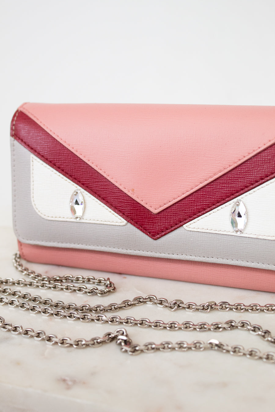 Pink and white handbag with a chain detail on a light background