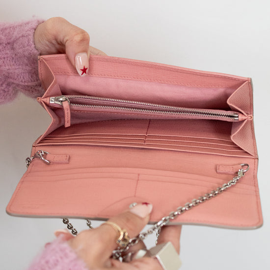 Pink wallet held open by a hand against a light background