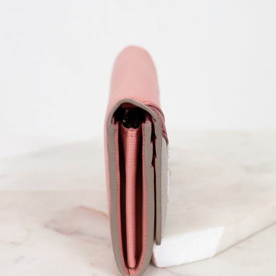 Pink side of wallet on a white marble surface