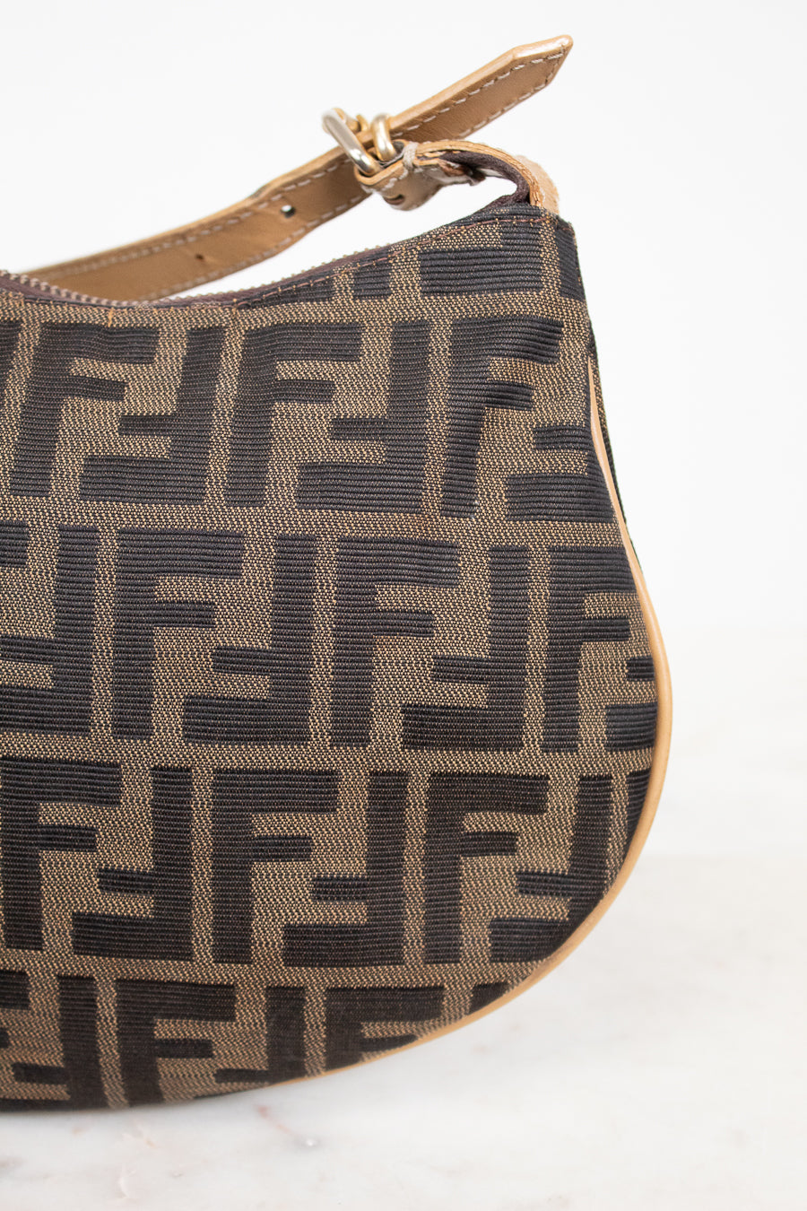 Brown handbag with black logo pattern on a white background