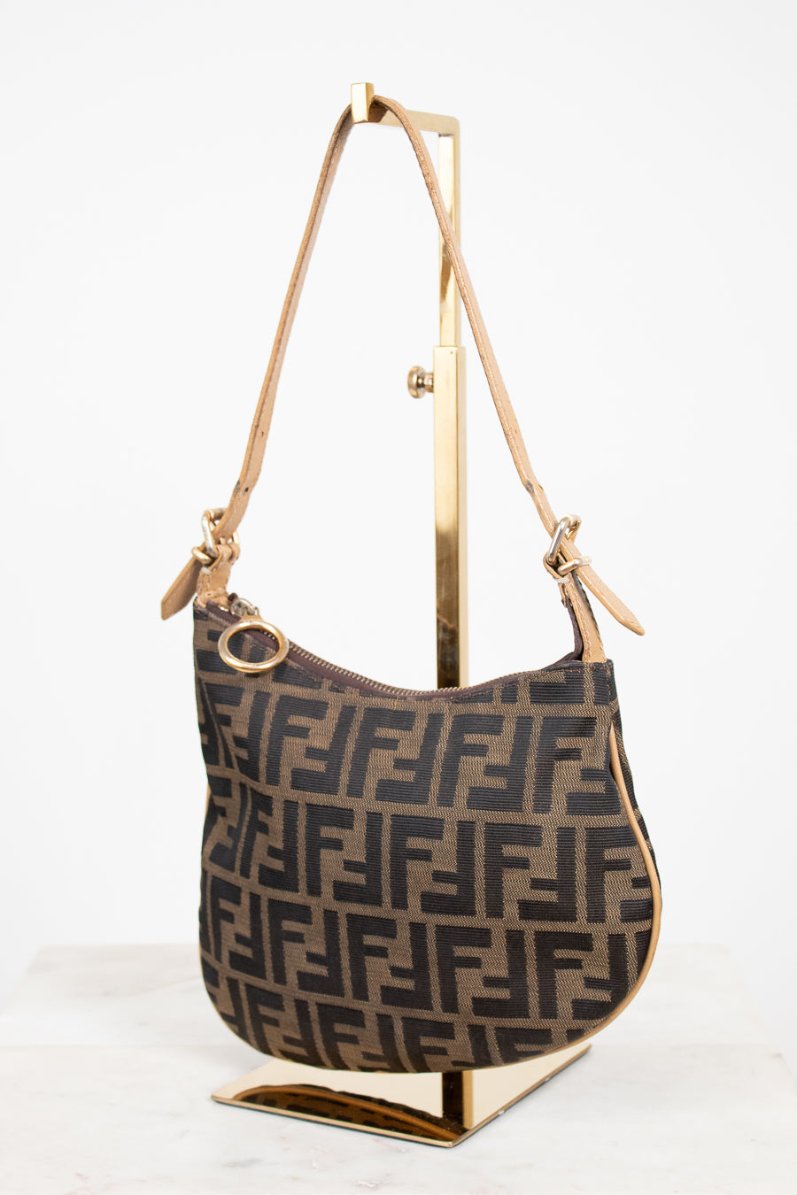 Designer handbag with brand logo on a stand against a white background