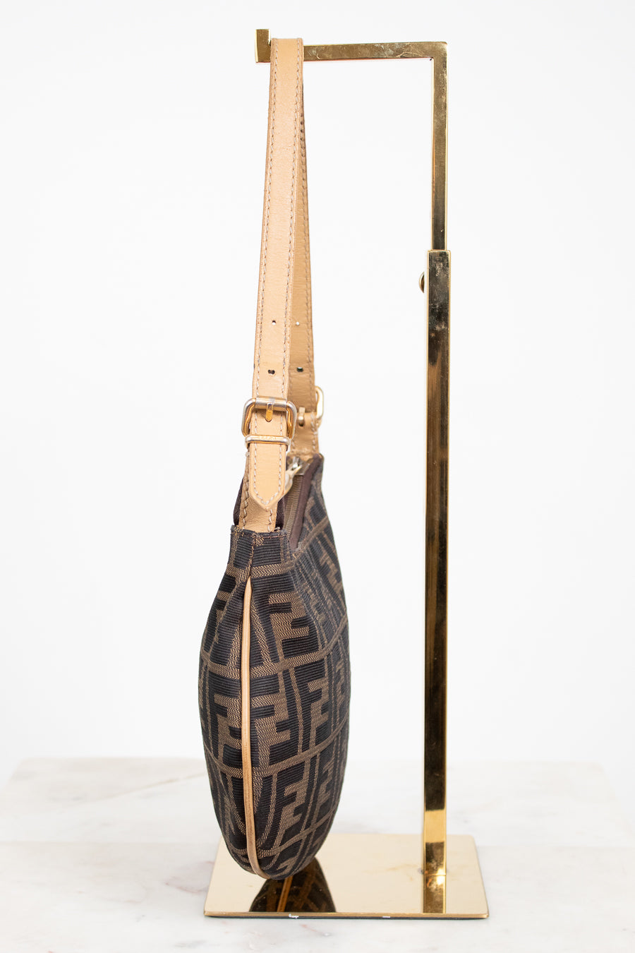 Designer handbag with a geometric pattern on a stand against a white background