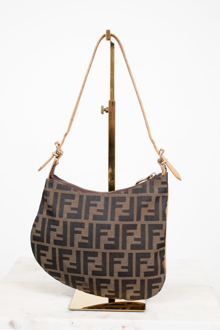 Designer handbag with a distinctive pattern on a stand against a white background