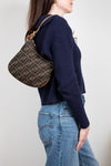 Person wearing a navy sweater and blue jeans, holding a patterned handbag.