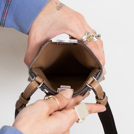 Person holding open a brown phone holder showing brown interior with a plain background
