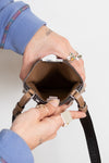 Person holding open a brown phone holder showing brown interior with a plain background