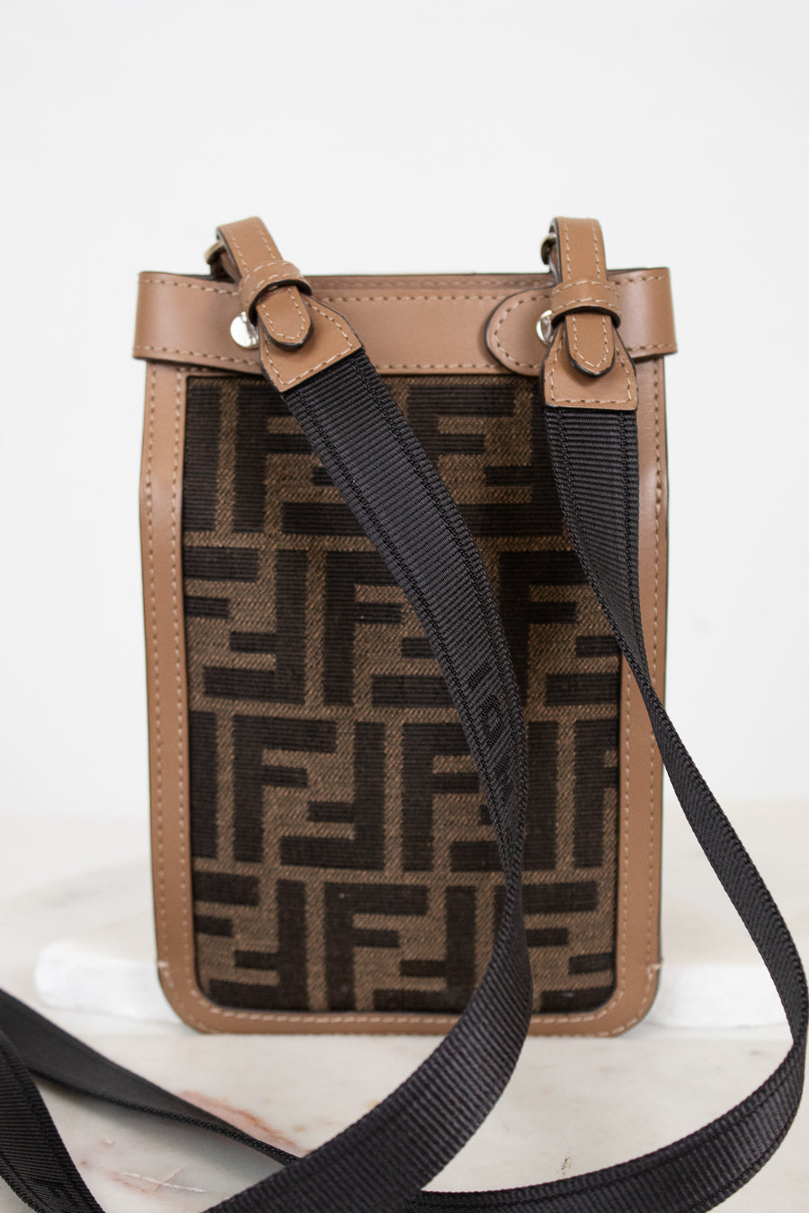 Brown crossbody phone holder with black strap on a white background