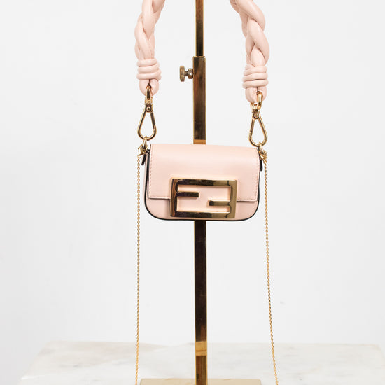 A light pink leather handbag with a gold-tone Fendi double-F logo buckle and a thick braided top handle, displayed on a gold stand against a white background.
