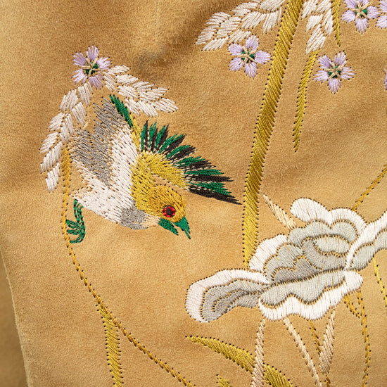Close-up of embroidered bird and floral design on beige fabric
