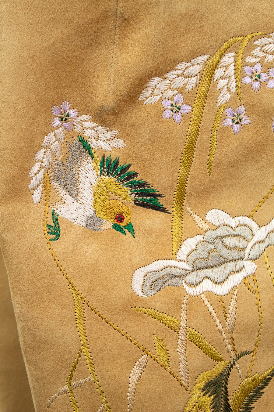 Close-up of embroidered bird and floral design on beige fabric