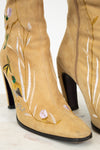 Tan suede boots with floral embroidery on a white background