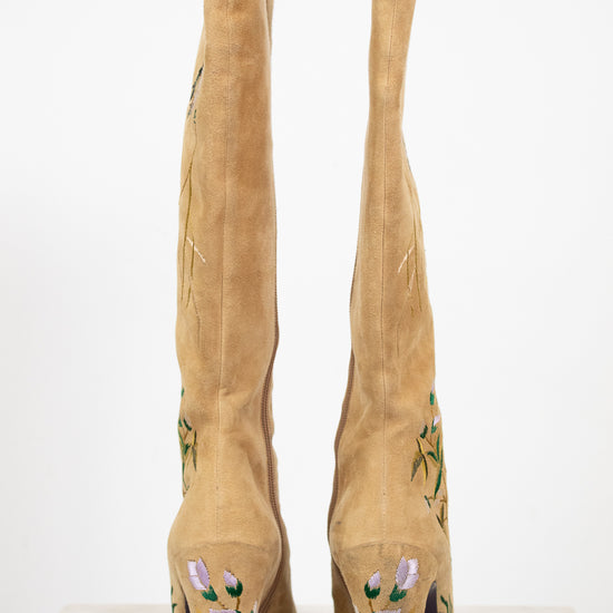Tan knee-high boots with floral embroidery on a white background