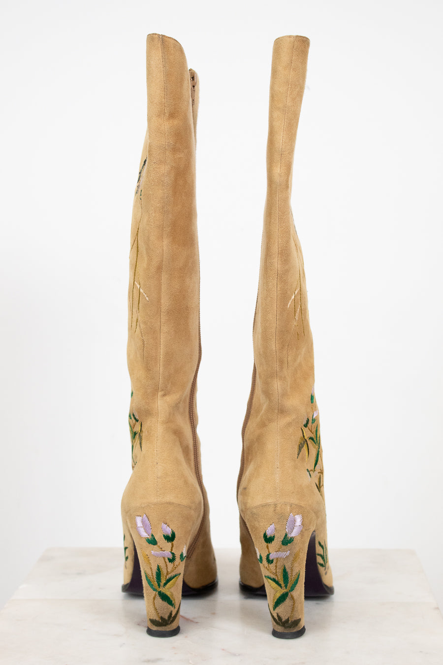 Tan knee-high boots with floral embroidery on a white background