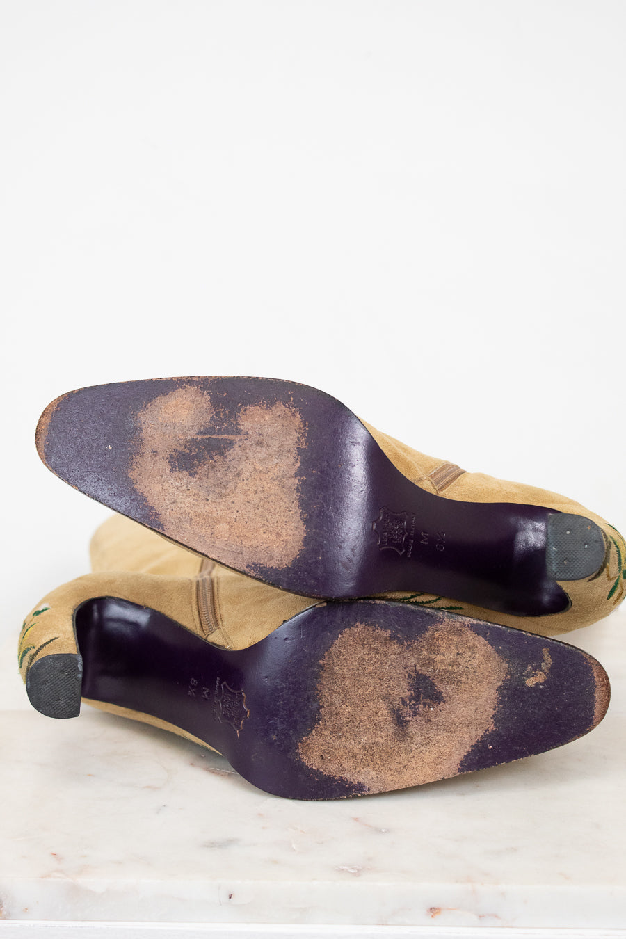 Pair of worn shoes with dark soles on a light background
