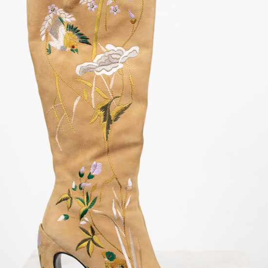 Beige knee-high boot with floral embroidery on a white background